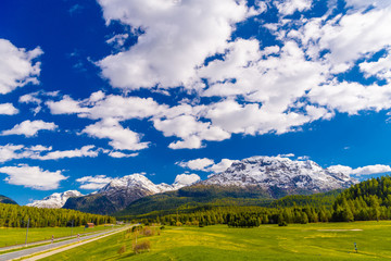 Green fields and Alps mountains coevered with forest, Samedan, M