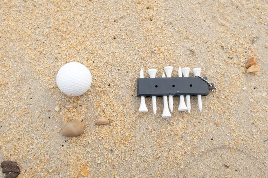 Golf ball with tee are on sandy beach, idea for golfer on holiday, golfer addicted to golfing