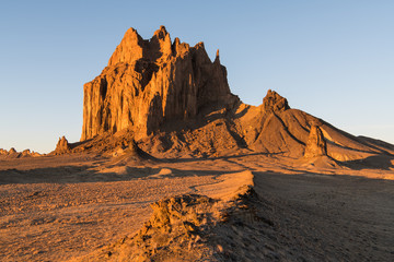 Winding road and ridge lead to the high peak of Shiprock in New Mexico in dramatic early morning light