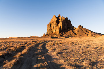 Fototapeta na wymiar Road curving through a vast landscape to the rock formation of Shiprock in New Mexico