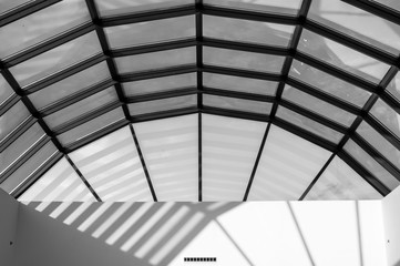 Obraz premium Modern glass roof with steel grid frames. Skylight rooftop window with symmetrical grid steel beams. Architectural detail and design on glass rooftop