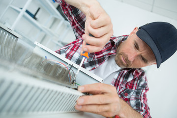Man using screwdriver on electric heater