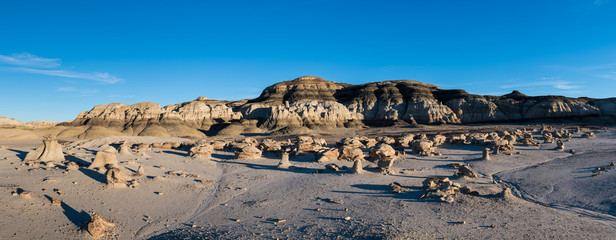 Panoramic alien landscape of the "Cracked Eggs" rock field and rock formations in late afternoon sun in the Bisti Badlands in New Mexico