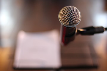 microfone em primeiro plano con mesa e papel al fundo e desfocados