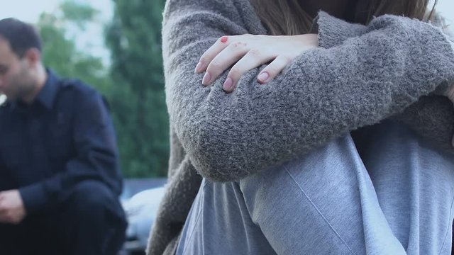 Policeman interrogating eyewitnesses, sad woman crying about her child death