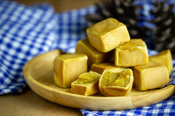 Chinese cakes dice shaped and dry pine flower are placed on a brown wooden table and have blue patterned tablecloths.