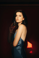 Thoughtful woman with champagne in dark room