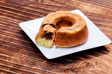 close-up on circular cake on white plate on wooden board