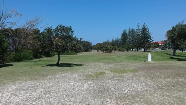 A grassy Lawn revealing a clean blue australian Beach.