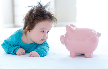 Baby boy with a piggy bank in childcare costs or savings theme