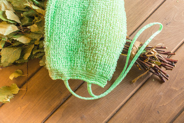 Green sponge with a birch broom lie on a shelf in a bath
