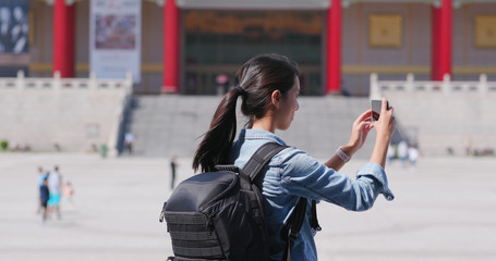 Fototapeta premium Travel woman take photo on cellphone in Chiang Kai shek Memorial Hall