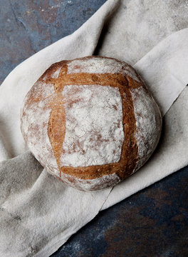 An artisan loaf of bread cools on a cloth.