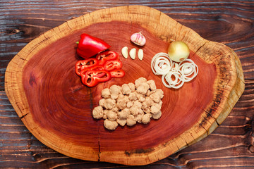 pieces of raw soy meat on wooden board, garlic, onion and red bell peppers