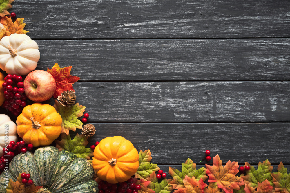 Wall mural top view of autumn maple leaves with pumpkin and red berries on old wooden background. thanksgiving 