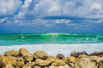 Turquoise rolling wave slamming on the rocks of the coastline