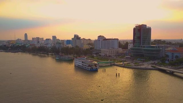 Aerial flying along the idyllic harbor with cruise ships waiting for tourists on a golden lit summer evening in Vietnam