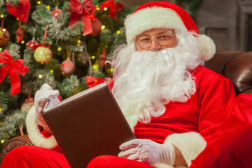 Naklejka premium Santa Claus sitting at his home in a comfortable chair and readi