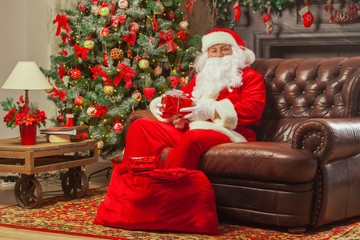 Santa Claus with giftbox on background of sparkling firtree. Chr