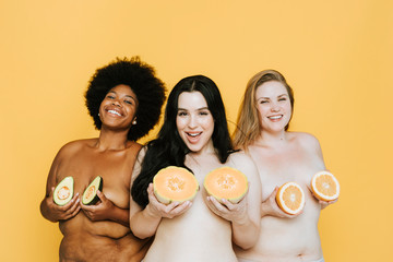 Diverse curvy nude women holding fruits over their breasts
