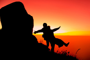 Fototapeta na wymiar Out of focus of : Silhouette cliff or peak with happy young man and young woman on high cliffs at sun set.Beautiful nature scenes.