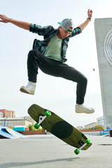 Full length portrait of contemporary young man doing skateboard stunts outdoors in extreme park © Seventyfour