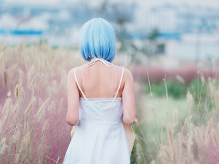 Rear view of beautiful young Chinese woman wearing white halter dress standing in the middle of...