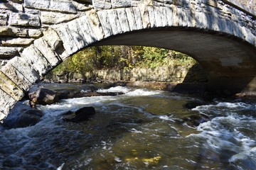 Fototapeta na wymiar River running under a stone bridge