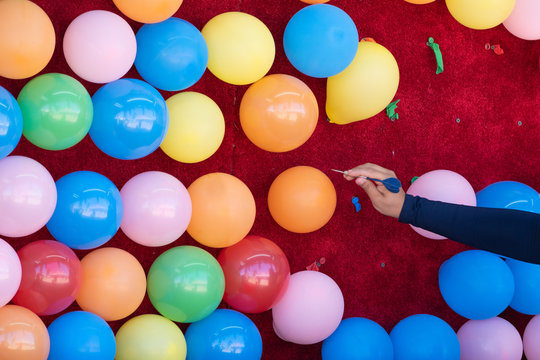 Woman popping colorful balloons with a dart.