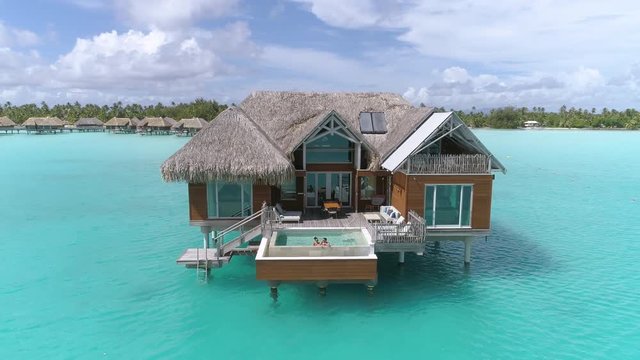Aerial - Couple enjoying in the pool at their overwater villa in Bora Bora 
