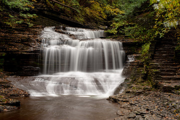 Fototapeta na wymiar Waterfall drapes the rocks in gorge.