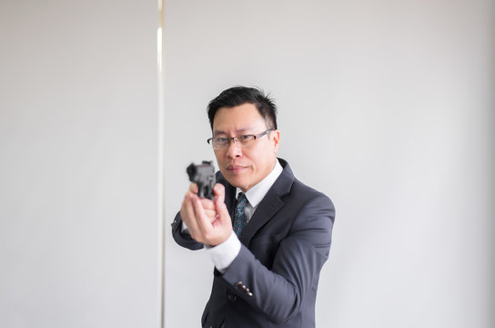Hands asian man in suit holding gun and aiming to you with automatic guns