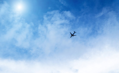 Naklejka na ściany i meble Airplane in the sky on a background of blue sky and white clouds.