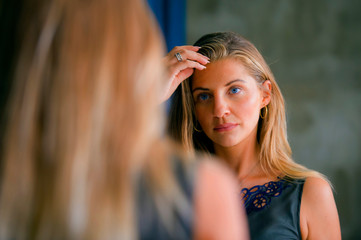 Naklejka premium young beautiful and happy blond woman enjoying shopping trying out clothes in the mirror at vintage and cool beauty fashion store smiling cheerful having fun