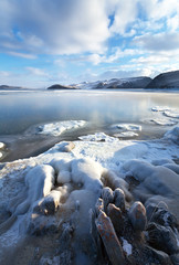 Obraz premium Lake Baikal in December. Beautiful winter landscape with thin ice in the Strait of Olkhon Gate and the ice-covered shore on a sunny frosty day