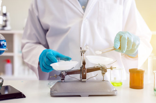 Chemist hand using scales weighing with medicine in lab