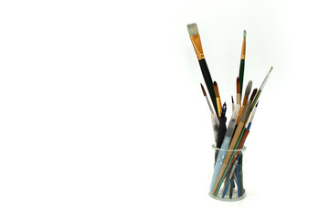 brush and other art tools in glass jar on white background