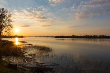 Summer sunset over a calm lake surrounded by forest