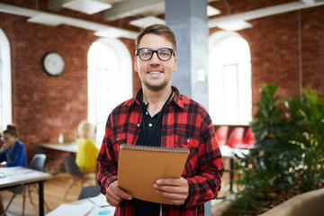 Creative guy in casualwear holding notepad with working and organization notes