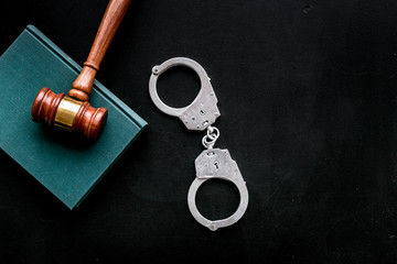 Fototapeta na wymiar Arrest concept. Metal handcuffs near judge gavel and law book on black background top view space for text