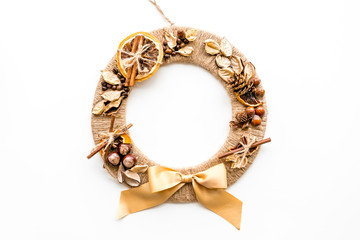 Creative, unusual christmas wreath made of thread, dry fruits and nuts on white background top view copy space