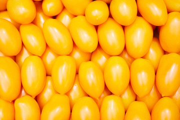Many orange tomatoes stacking together, food background for shopping and organic food topics