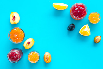 Jams different tastes made of fruits and berries near pieces of fruits on blue background top view space for text