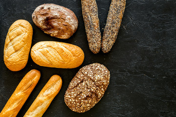 Set of fresh homemade bread. Bread assortment. Loaf, baguette. White and brown bread on black background top view copy space