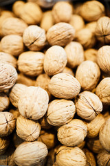 Heap of in-shell walnuts stacking under light, food background