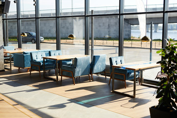 Windows of modern cafe and row of tables and chairs along them inside
