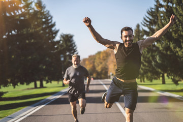 The two men running on the road in the park on the sunny background