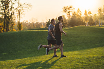 The two men running on the grass in the park