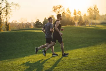 Fototapeten The two sportsmen running on the grass in the park © realstock1