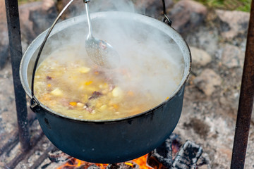 Cooking food in a pot on campfire. Summer camping concept.